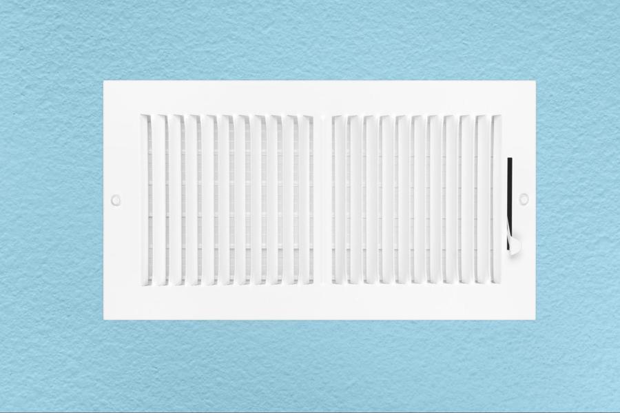 White open air vent affixed in a sky blue wall.